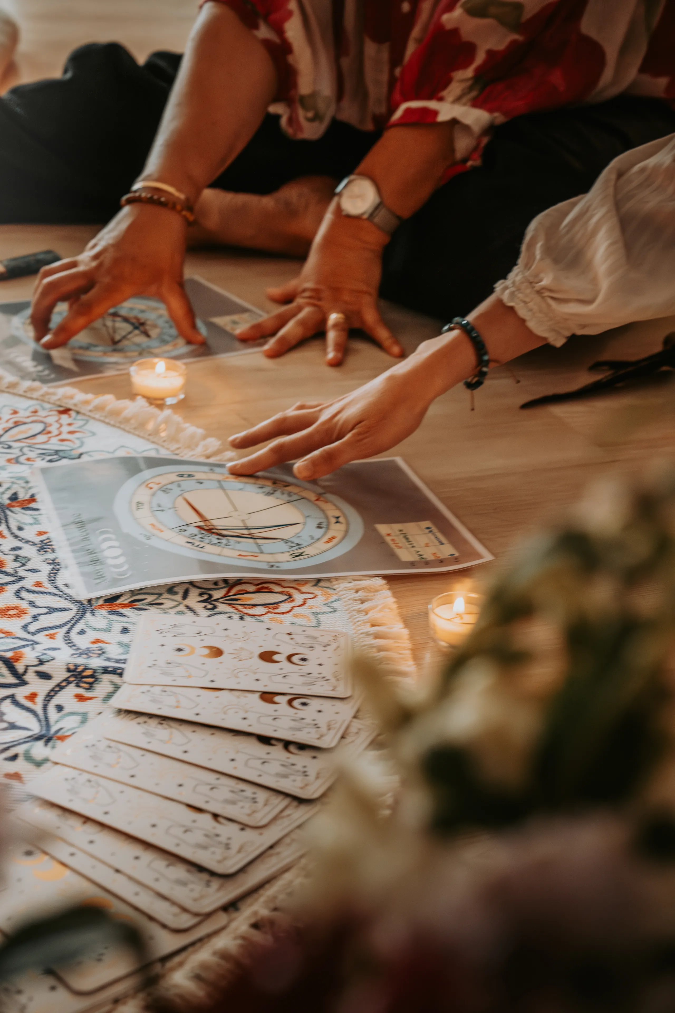 Des mains posées autour d’une carte du ciel imprimée, près d’un jeu de cartes aux croissants de lune étalé en éventail.